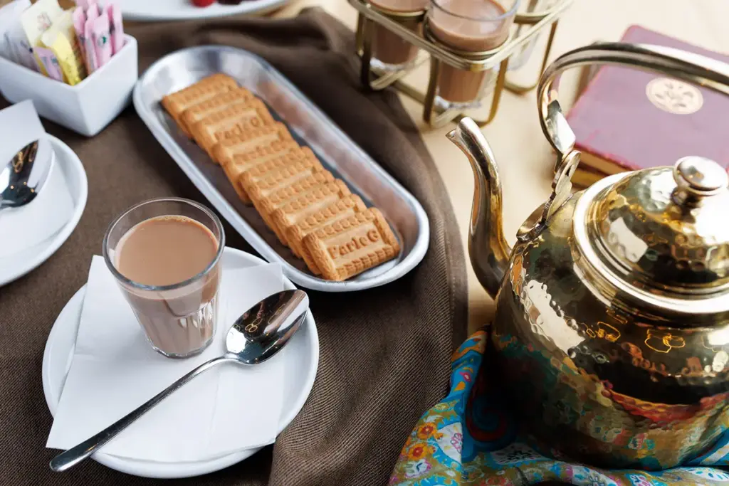 Chai served with biscuits and a golden teapot at Central by Saffron Valley.