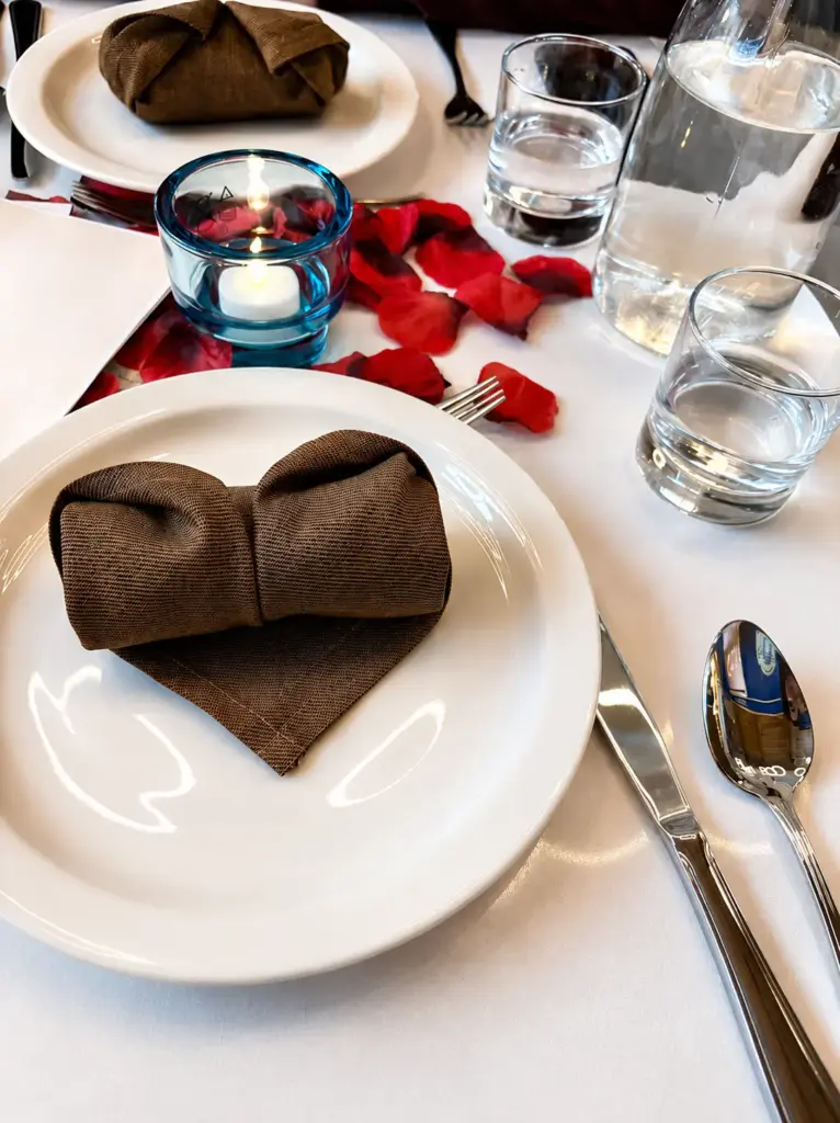 Elegant private dining table setting with folded napkins, candlelight, glassware, and rose petals at Central by Saffron Valley.