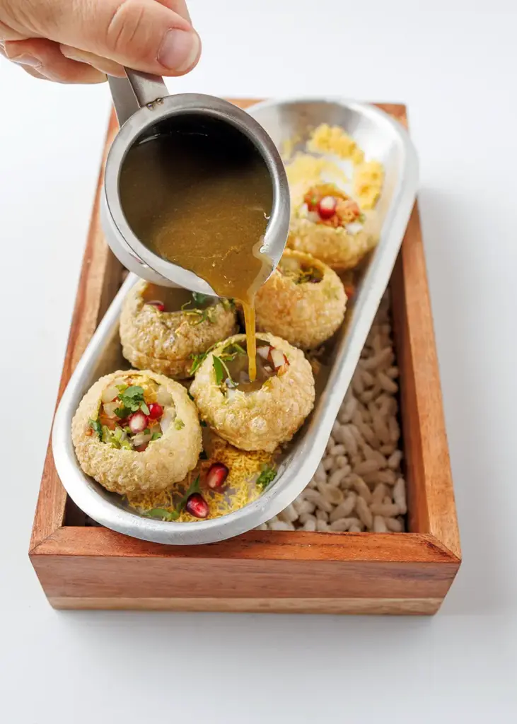 Pani puri Indian appetizer being filled with spiced water at Central by Saffron Valley.